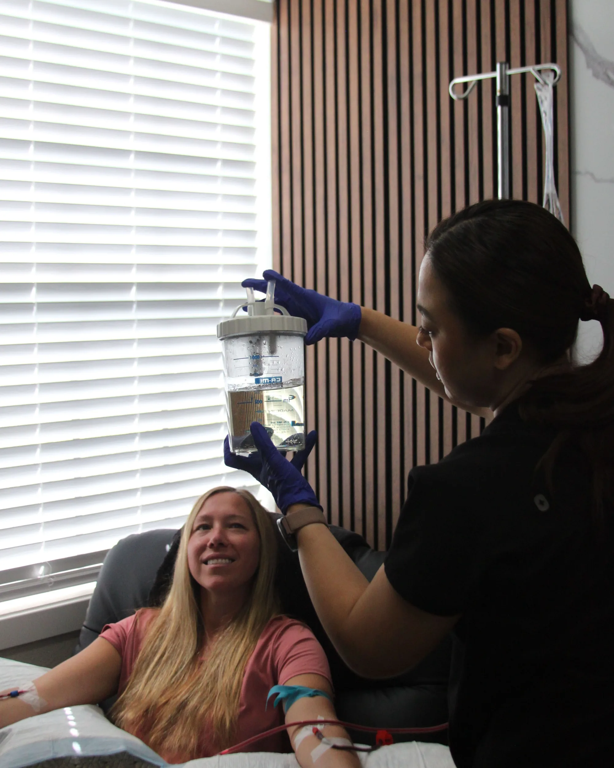 A clinician at SeaCoast Clinic holding the EBOO filter canister beside a patient during a session